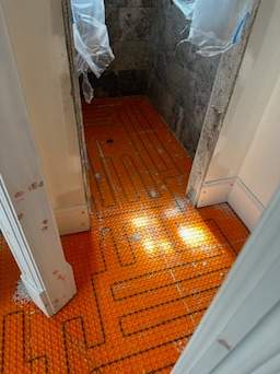 the image shows heated flooring installation with orange matting laid out in preparation for tiling or finishing touches